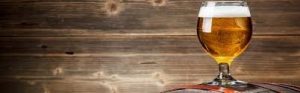 beer glass sitting on barrel against wood background